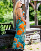 Woman wearing a colorful dress with an open back, standing outdoors.