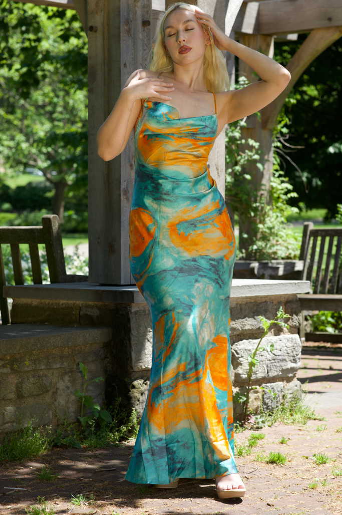 Woman in a colorful dress standing outdoors with greenery in the background