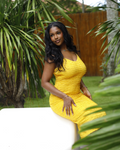 Woman in a yellow dress sitting outdoors with greenery around